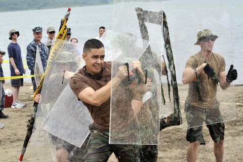 Construction Mechanic 2nd Class Nathan Breen, center, a native of Venice, Calif., and assigned to Naval Air Facility Misawa Public Works Department, shields his flag bearer from water-balloon fire during the 2013 Navy Mi