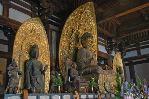 Inside of the Eastern Golden Hall (東金堂, tōkon-dō) of Kōfuku-ji in Nara, Japan. The central image, a sitting Yakushi Nyorai, is framed by two standing attendants: Nikkō and Gakkō Bosatsu. Together the three statues form a