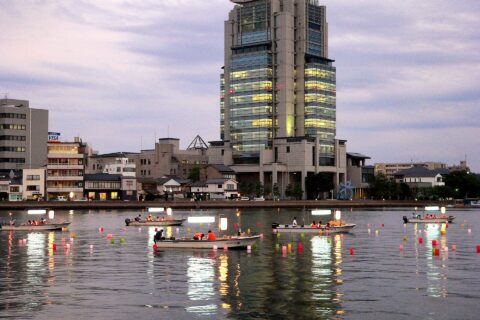 People in boats placing lanterns onto Lake Shinji at the end of the Obon festival. Matsue city is in the background. Photographer: James Alexander Jack Date: 16th of August, 2007 Location: Matsue, Japan.