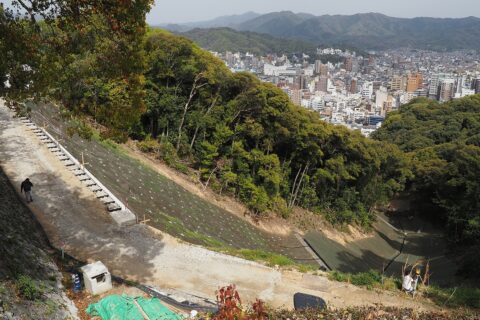 ​2024年7月12日に発生した松山城東斜面の土砂崩れの復旧工事現場。高強度ネットと水路が見える。2026年4月6日撮影。2026年5月29日工事完了。