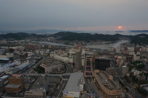 山口県下関市豊前田町の海峡ゆめタワーからの展望。手前は竹崎町、大和町。100～200m幅の小瀬戸を挟んで彦島。左奥に関門海峡と北九州市が見える。写真右上の大きめの島は六連島。左下手前は国際フェリーターミナル。中央やや右下のピデストリアンデッキの突き当りはJR下関駅で、撮影した2013年夏は建設中。