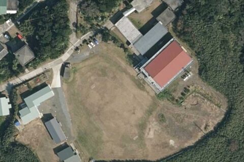 鹿児島県鹿児島郡十島村にある十島村立悪石島（あくせきじま）学園の空中写真。右上の建物が校舎で、赤屋根の建物は屋内運動場。校庭を挟んだところにある建物は悪石島多世代交流施設や山海留学生用の寄宿舎（悪石島寮）などである。2022年2月撮影の空中写真「CKU202110-C13-9」を加工して作成。